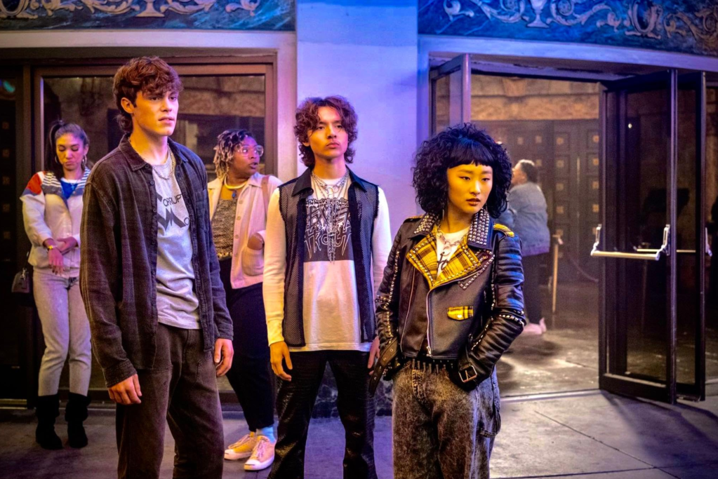 A still from the film 'Freaky Tales' featuring Lucid (Jack Champion) and Tina (Ji-young Yoo). They are standing outside in front of a fancy building.