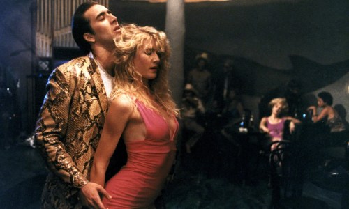 Sailor (Nicolas Cage) and Lula (Laura Dern) dancing at a bar in Wild at Heart. Sailor is wearing his snakeskin jacket and Lula is wearing a body-con pink dress. 